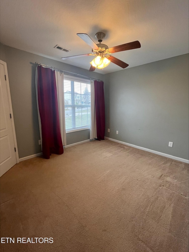 carpeted spare room featuring visible vents, ceiling fan, and baseboards