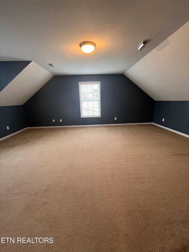 bonus room with visible vents, a textured ceiling, baseboards, and vaulted ceiling