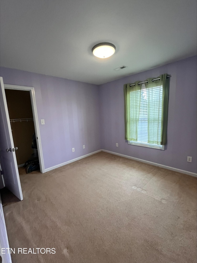 carpeted spare room featuring visible vents and baseboards