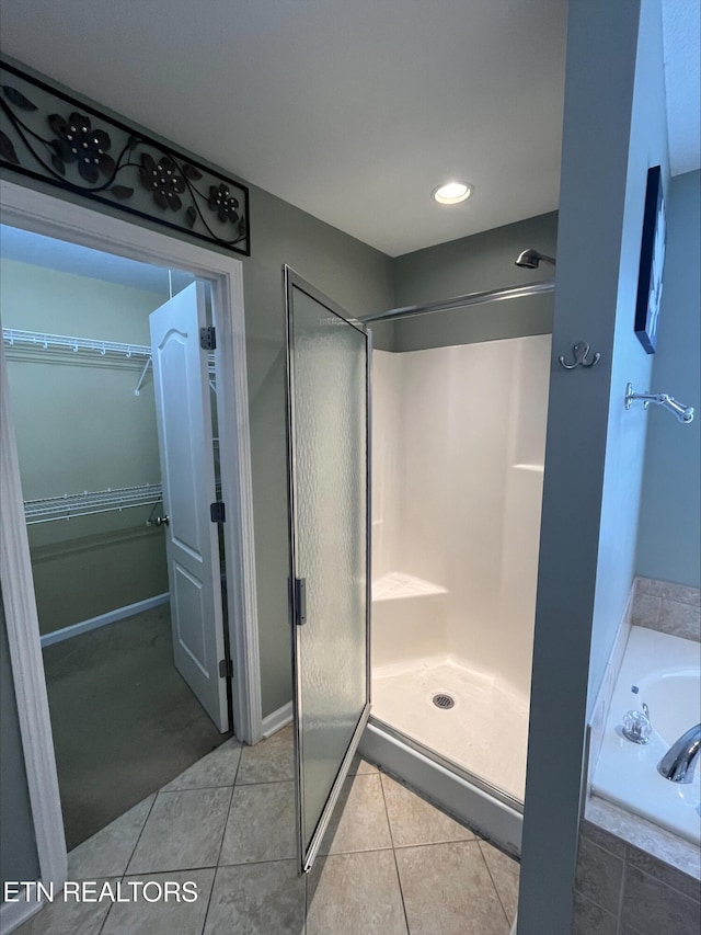 full bath featuring a walk in closet, a garden tub, a stall shower, and tile patterned flooring