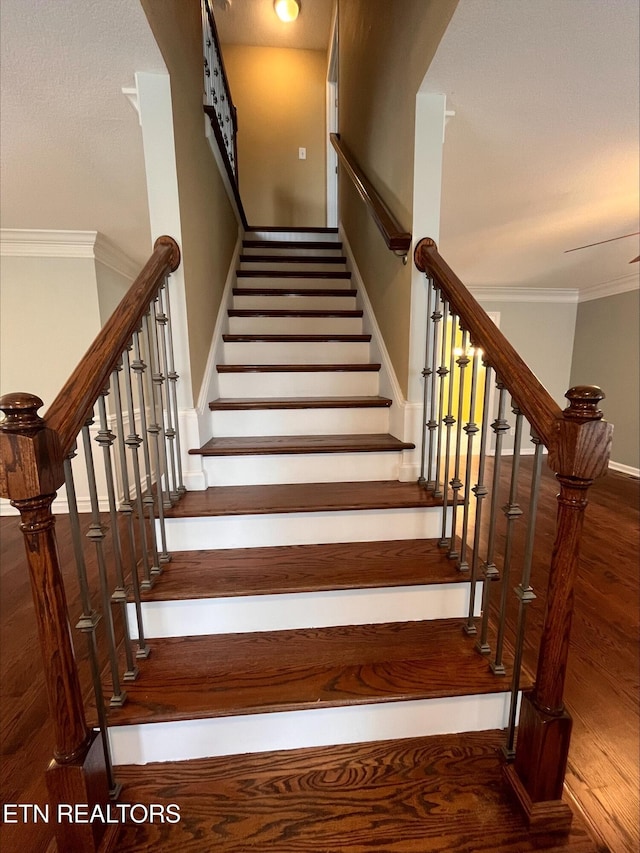 stairs featuring wood finished floors and crown molding