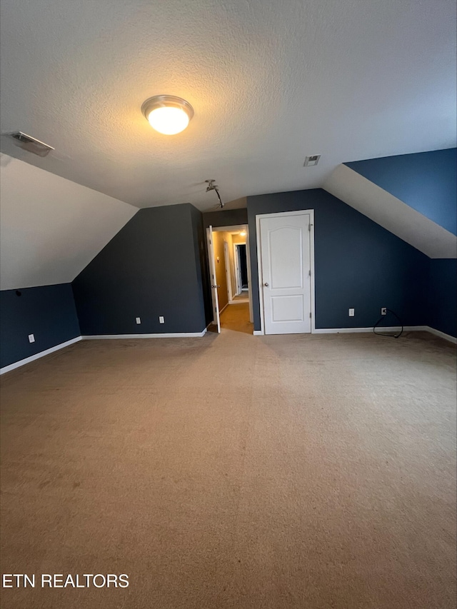 additional living space with baseboards, lofted ceiling, a textured ceiling, and carpet flooring