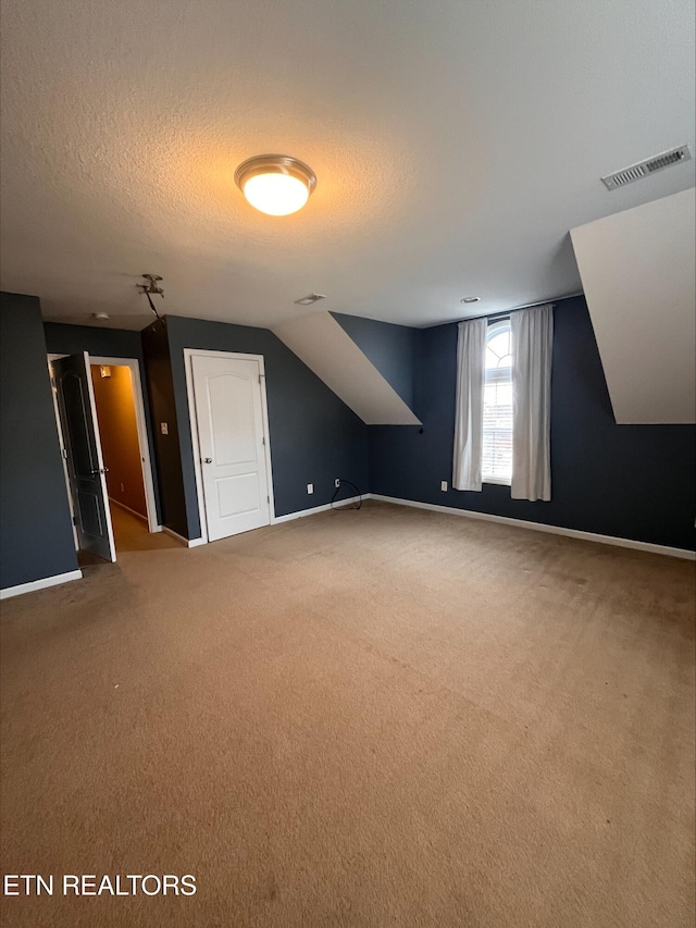 additional living space featuring visible vents, carpet floors, a textured ceiling, and baseboards