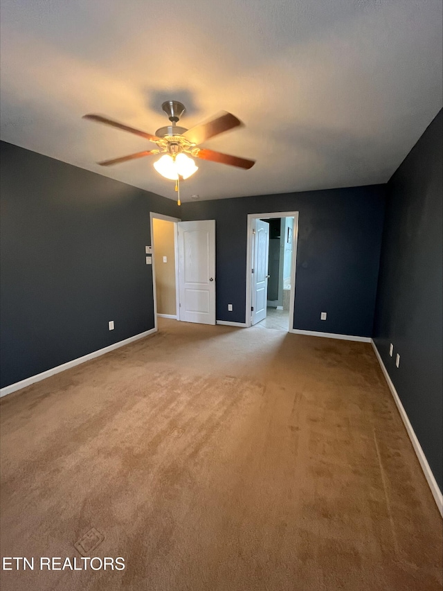 unfurnished bedroom with connected bathroom, baseboards, carpet floors, and ceiling fan