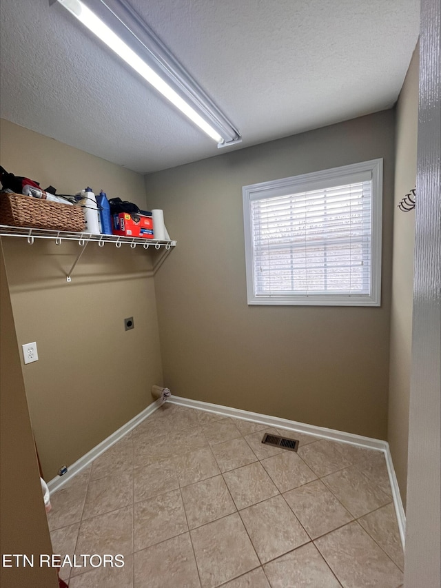 laundry room featuring visible vents, a textured ceiling, baseboards, hookup for an electric dryer, and laundry area