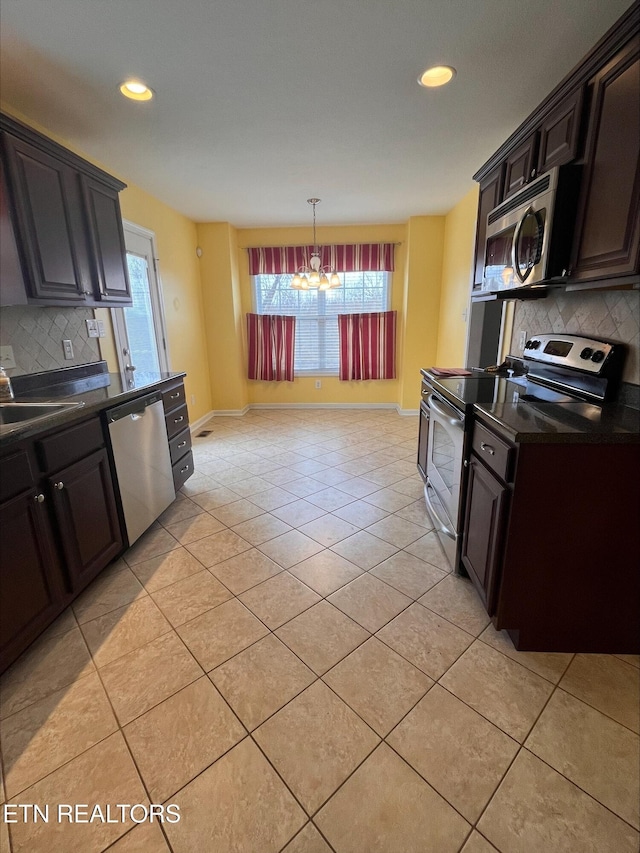 kitchen featuring a sink, backsplash, dark countertops, appliances with stainless steel finishes, and an inviting chandelier