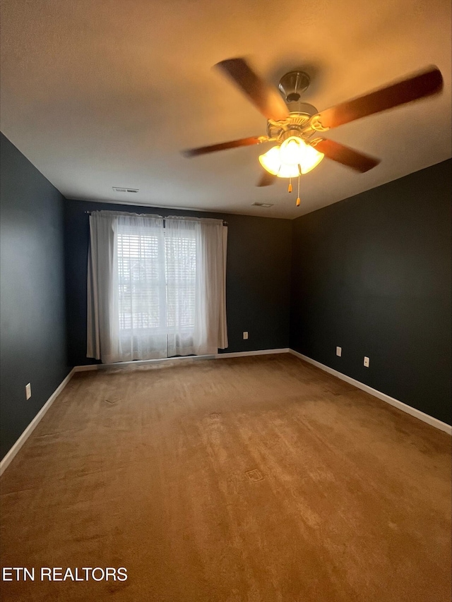 carpeted empty room featuring a ceiling fan and baseboards