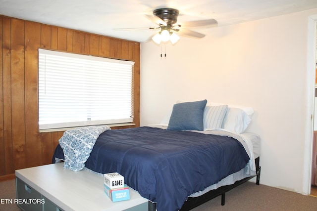 carpeted bedroom with wood walls and ceiling fan