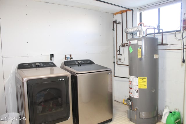 washroom with concrete block wall, laundry area, water heater, washer and dryer, and tile patterned floors