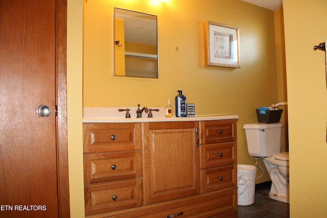 bathroom with toilet, vanity, and tile patterned flooring