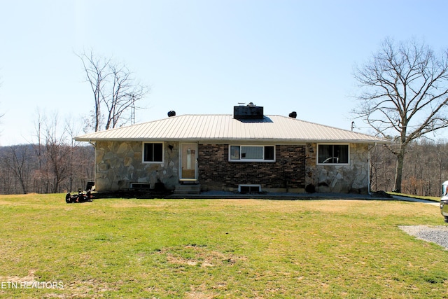 ranch-style home featuring stone siding, a front yard, metal roof, brick siding, and a chimney