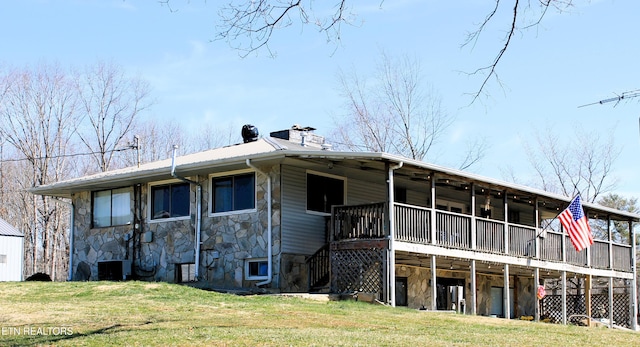 back of house with central air condition unit, a lawn, stone siding, and a chimney