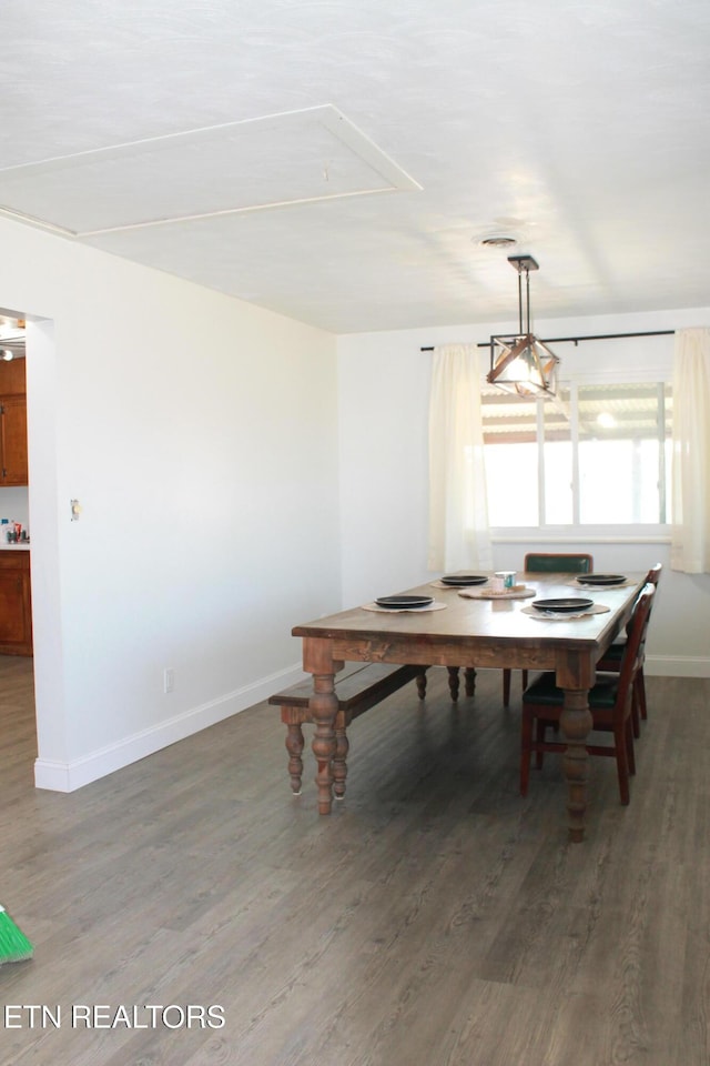 dining space with attic access, baseboards, and wood finished floors