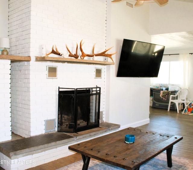 living area with baseboards, wood finished floors, and a fireplace