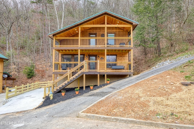 rustic home featuring a balcony, a view of trees, and board and batten siding