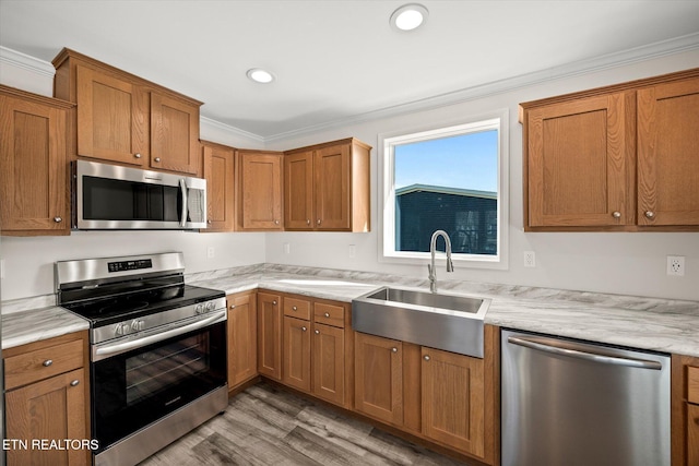 1600 Anna Maria Ln, Cookeville, TN 38501 - kitchen featuring stainless steel appliances, a sink, light wood-style floors, brown cabinetry, and ornamental molding