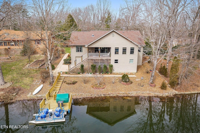 back of property with stairway, a water view, and roof with shingles