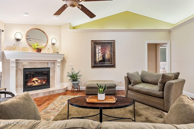 living area featuring baseboards, vaulted ceiling, a fireplace, wood finished floors, and a ceiling fan