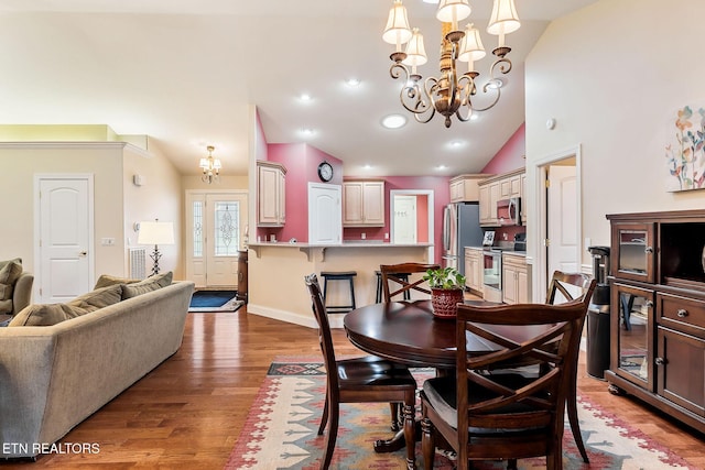 dining room featuring a notable chandelier, lofted ceiling, wood finished floors, recessed lighting, and baseboards