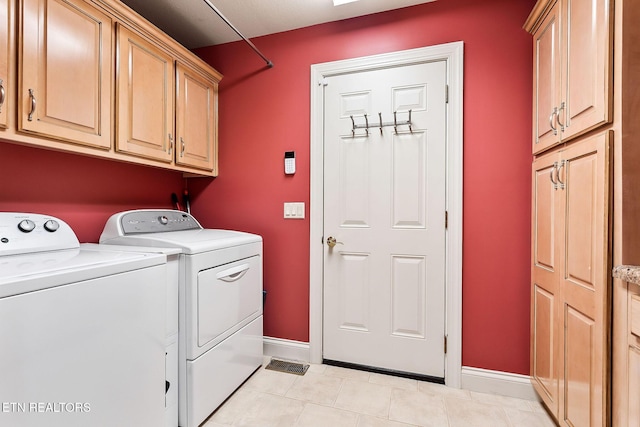 laundry area featuring light tile patterned flooring, cabinet space, baseboards, and separate washer and dryer