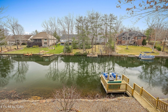 view of dock with a residential view, a yard, and a water view