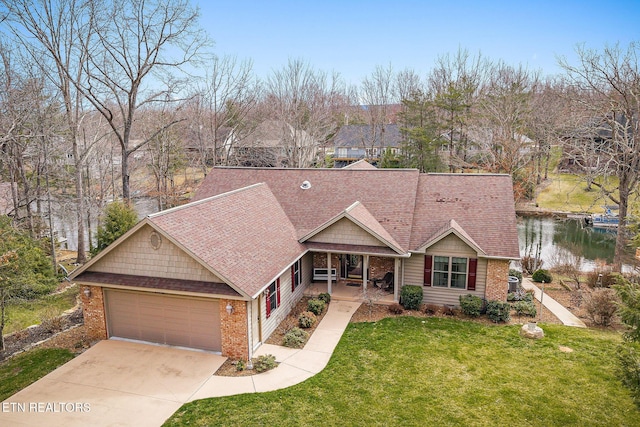 view of front facade with brick siding, a water view, concrete driveway, a front yard, and covered porch