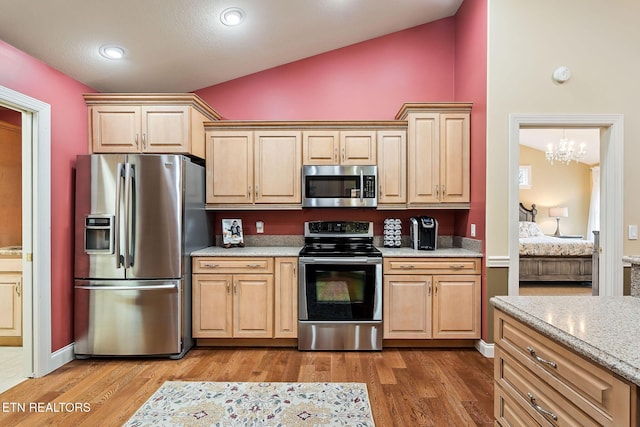 kitchen with light stone countertops, lofted ceiling, light brown cabinetry, stainless steel appliances, and light wood-type flooring