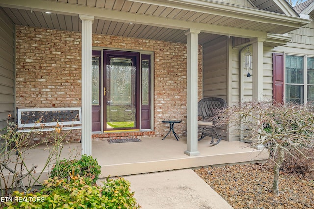 entrance to property featuring brick siding and covered porch