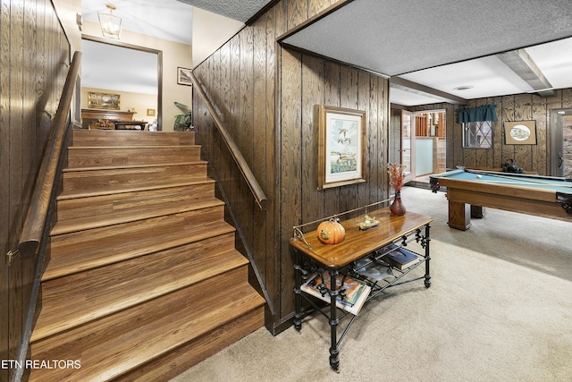 stairs featuring wooden walls, carpet, and a textured ceiling