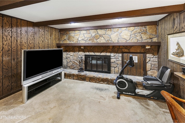 interior space featuring a stone fireplace, wood walls, and carpet floors