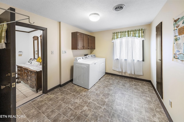 laundry room featuring visible vents, baseboards, a textured ceiling, and washing machine and clothes dryer