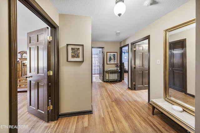 hall featuring a textured ceiling and light wood finished floors