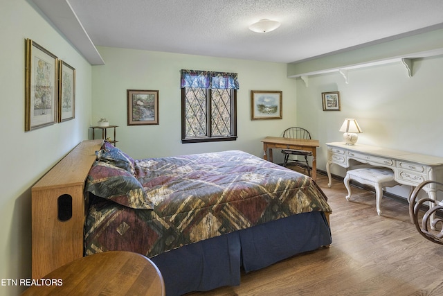 bedroom with a textured ceiling and wood finished floors