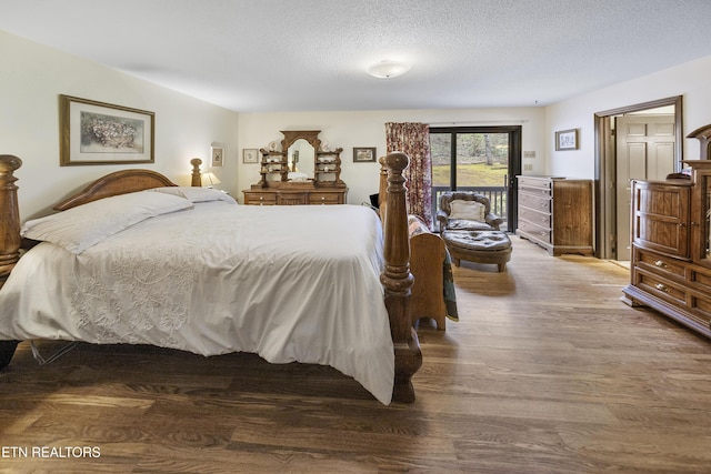 bedroom with access to outside, a textured ceiling, and wood finished floors