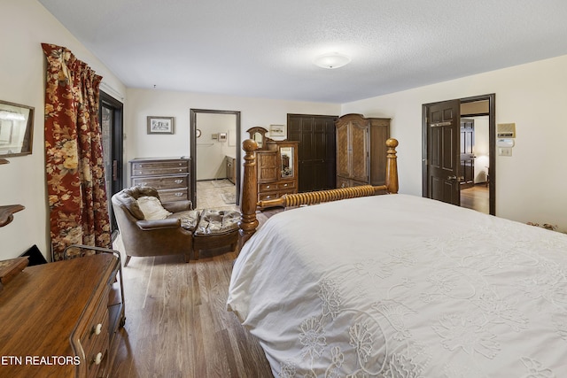 bedroom with a textured ceiling, wood finished floors, and ensuite bathroom