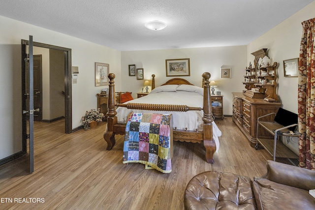 bedroom featuring wood finished floors, baseboards, and a textured ceiling