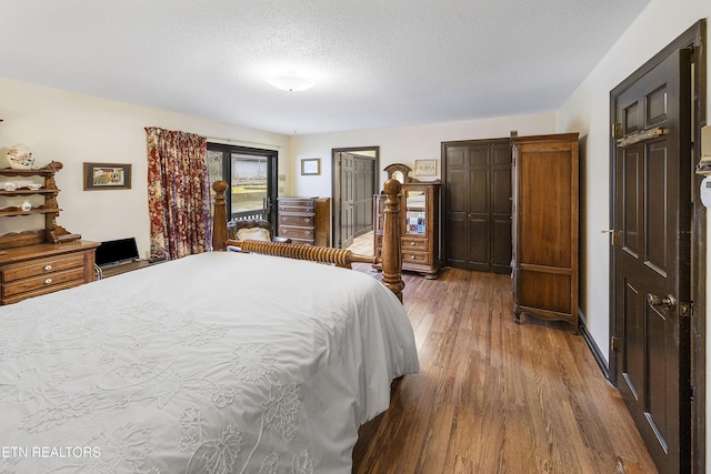 bedroom with wood finished floors, two closets, and a textured ceiling