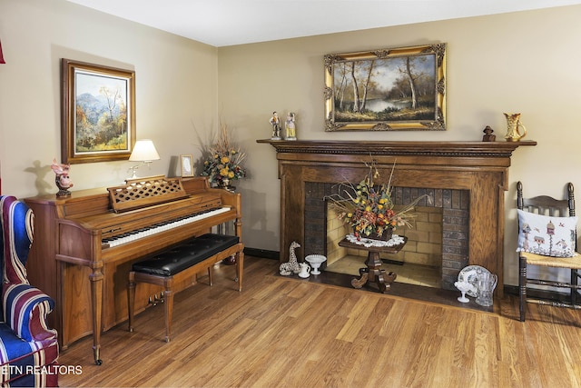 sitting room featuring a fireplace, baseboards, and wood finished floors