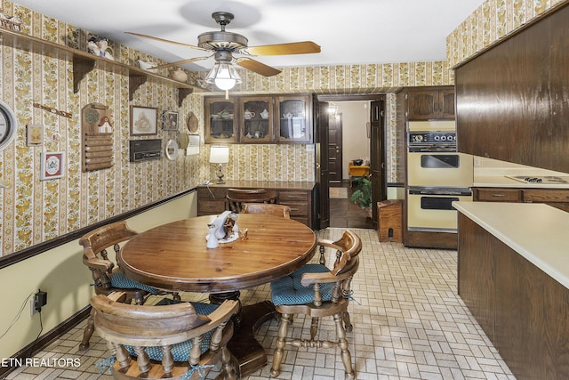 dining space with brick patterned floor, wallpapered walls, baseboards, and a ceiling fan