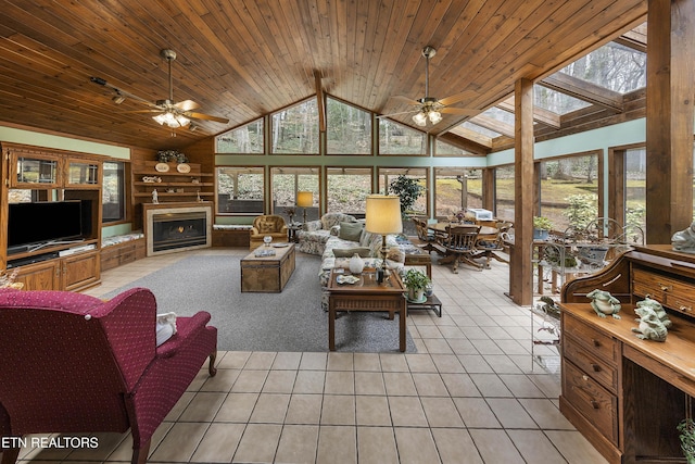 living room with a skylight, a lit fireplace, light tile patterned flooring, and wooden ceiling