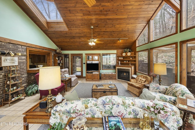 tiled living room with wooden ceiling, a skylight, plenty of natural light, and a lit fireplace