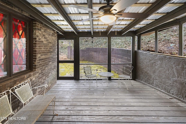 unfurnished sunroom featuring beamed ceiling and a ceiling fan