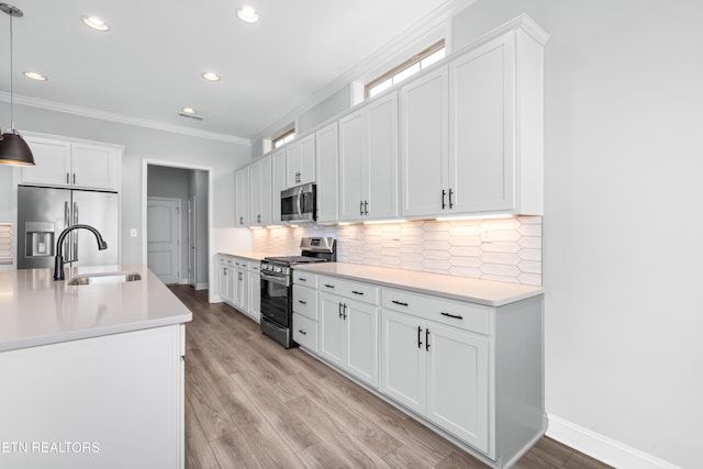 kitchen featuring light wood finished floors, a sink, decorative backsplash, stainless steel appliances, and crown molding