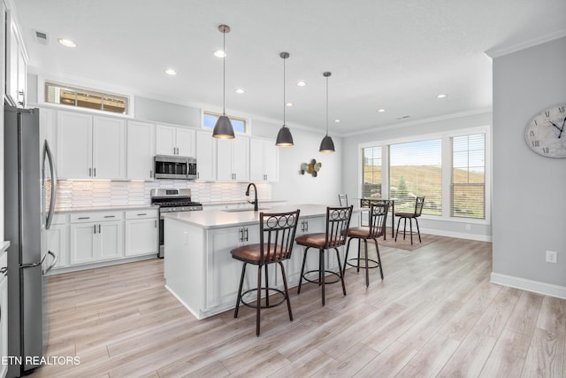 kitchen featuring visible vents, a sink, decorative backsplash, appliances with stainless steel finishes, and a kitchen island with sink