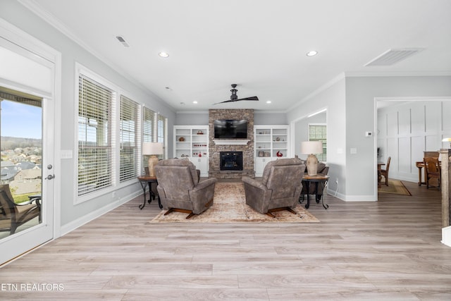 living area featuring a fireplace, crown molding, a ceiling fan, and visible vents