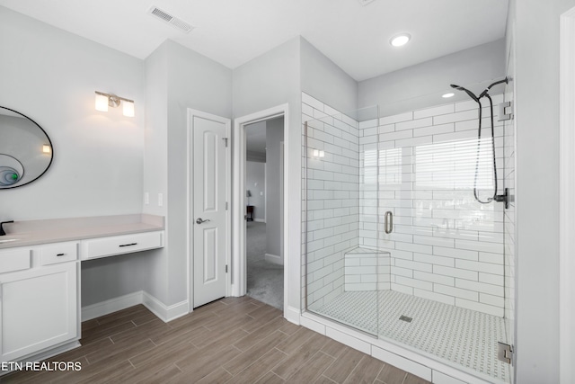 full bath with visible vents, a shower stall, baseboards, wood finish floors, and vanity