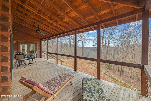 sunroom / solarium featuring a forest view, wood ceiling, a ceiling fan, and vaulted ceiling