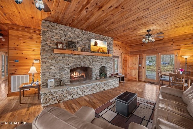 living area featuring visible vents, wooden walls, a fireplace, wooden ceiling, and hardwood / wood-style flooring