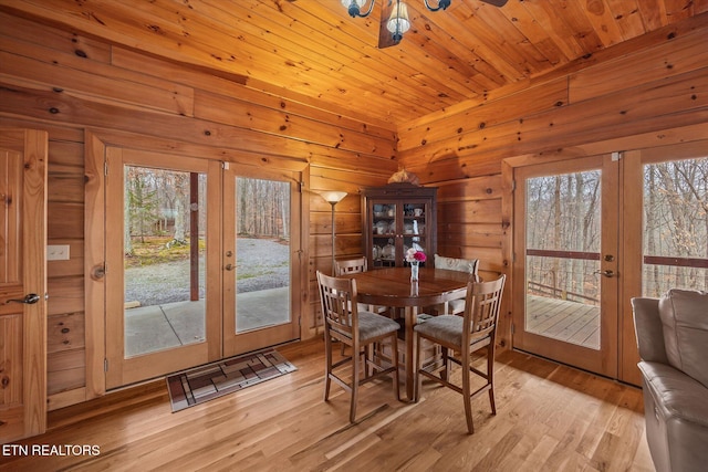 dining room with light wood finished floors, french doors, and wooden ceiling