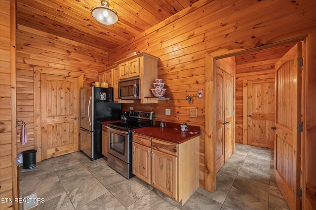 kitchen with wood ceiling, dark countertops, appliances with stainless steel finishes, and wood walls